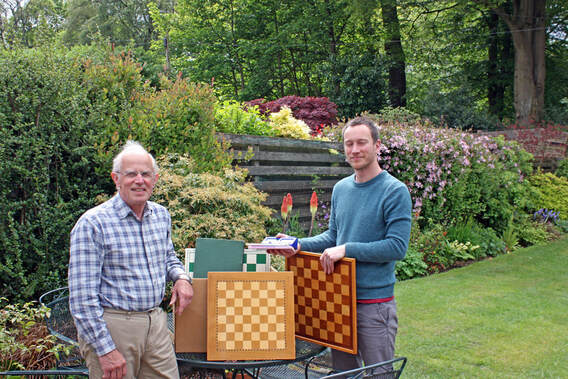 Bearsden's Mel Burt donating chess materials to Queens Park's Julien Papillon